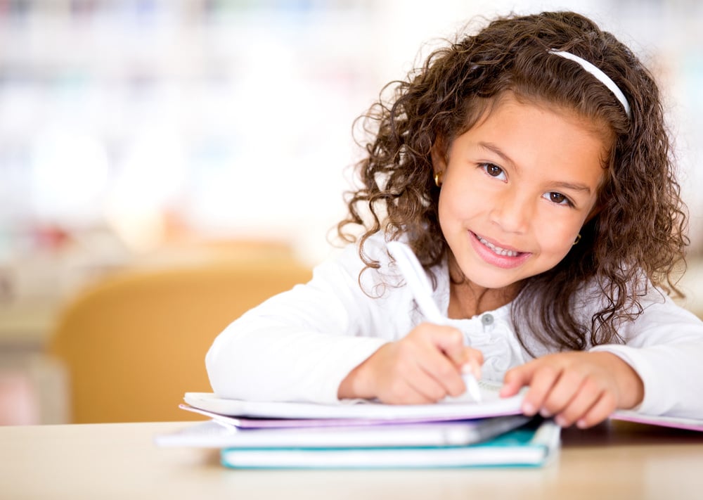 Cute little girl studying at the library and smiling