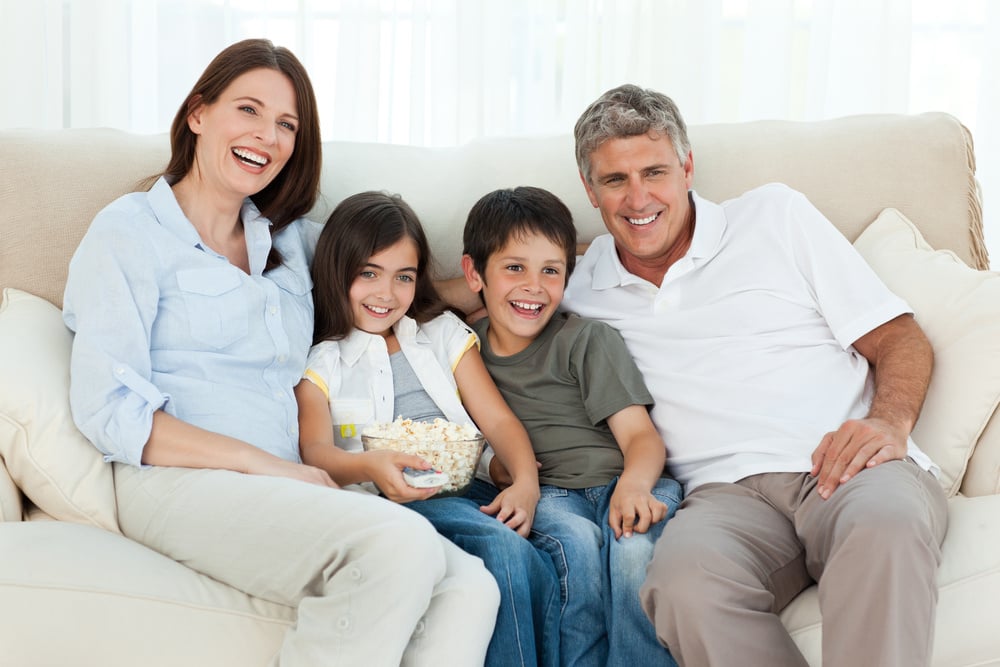 Family watching tv while they are eating popcorn