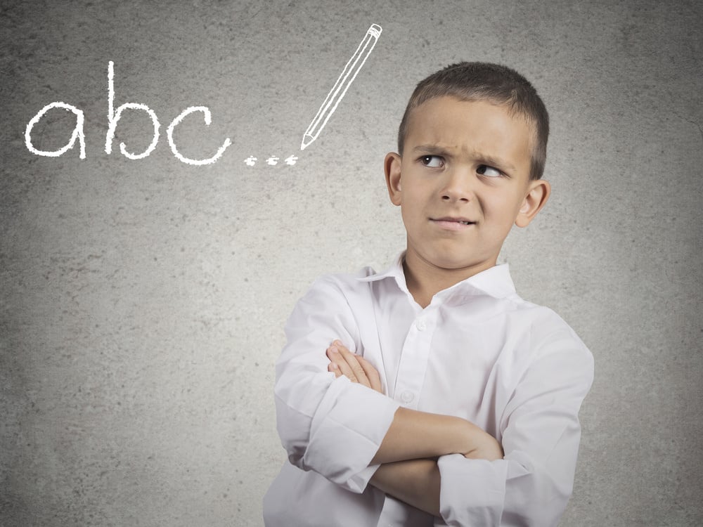 Unhappy young student in a classroom. Closeup portrait displeased boy looking skeptically on blackboard, doesnt like school, class, to learn, isolated grey wall background. Human face expressions