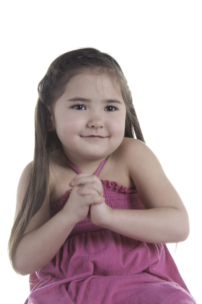 Girl of five with bright eyes and hopeful smile clasping her hands