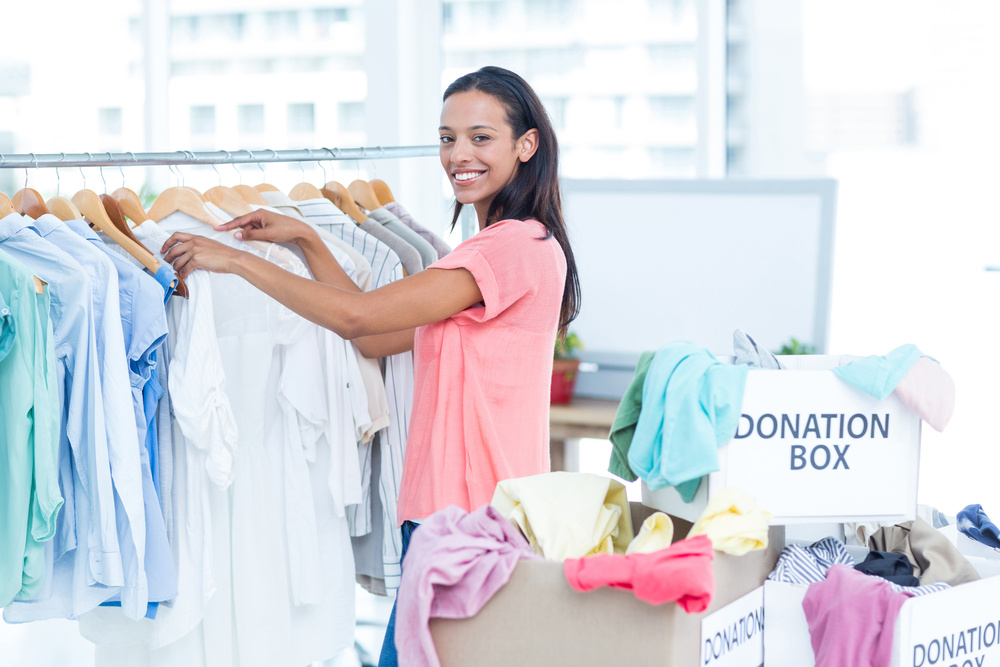 Portrait of a smiling young female volunteer separating clothes